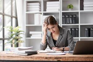 Young Woman Stressed at Work in Modern Office Environment, Overwhelmed by Paperwork and Deadlines, Experiencing Work-Related Stress and Anxiety, Struggling to Manage Tasks and Maintain Productivity photo