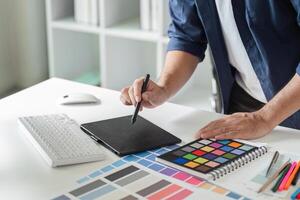 Creative Graphic Designer Planning a Project with Digital Tools and Color Swatches in a Modern Office Environment photo