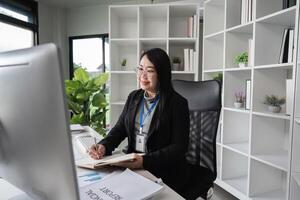 Middle-aged Business Woman Working in Modern Office Environment with Documents and Computer photo
