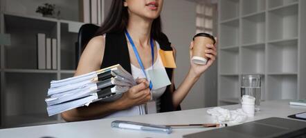 Focused Businesswoman Multitasking at Office Desk with Documents and Coffee in a Modern Workspace Environment photo