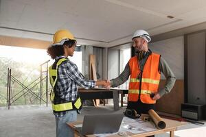 Engineering Team Planning Construction Work Indoors with Blueprints and Safety Gear, Shaking Hands in Agreement on a Building Site, Collaboration and Teamwork in Modern Architecture Projects photo