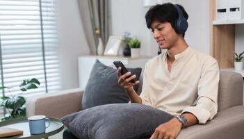 Young Man Relaxing on Sofa in Modern Living Room While Exploring Social Media on Smartphone photo