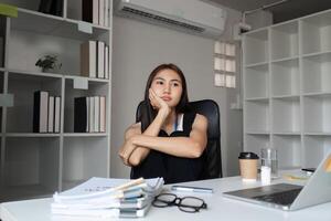 Bored Woman at Work Sitting at Desk in Modern Office with Laptop and Documents, Feeling Uninspired and Unmotivated During Work Hours photo