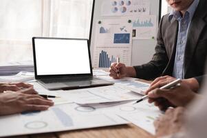 Business team working together on project with charts and laptop with white screen in modern office photo