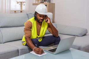 Construction worker in a safety vest makes a phone call while taking notes at home office photo