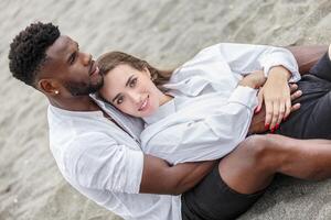 A couple embraces on a sandy beach, enjoying a sunny day while relaxing by the shore during the afternoon photo