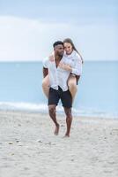 Woman climbs on man's back in a playful moment at Zapillo beach in Almeria, Spain during a sunny day. photo