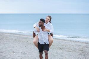 Couple enjoying a playful day at Zapillo Beach in Almeria, Spain, with a romantic piggyback ride under a cloudy sky photo