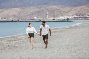 Couple strolling hand in hand along Playa del Zapillo beach in Almeria, Spain during a sunny day photo