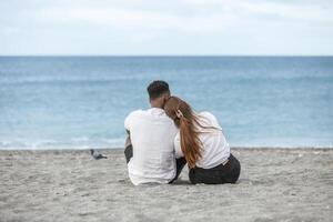 Couple sitting on the sand relaxing together on Zapillo Beach in Almeria, Spain, watching the waves on a calm afternoon. photo