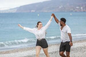 Couple joyfully dancing at Playa del Zapillo beach in Almeria, Spain, enjoying a sunny day by the sea together photo