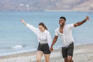 Couple joyfully running along the beach at Playa del Zapillo in Almeria, Spain on a sunny day photo
