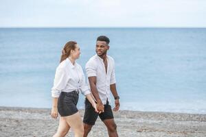 Couple walking hand in hand along the beach at Playa del Zapillo in Almeria, Spain during a sunny day photo
