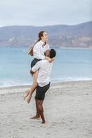 Couple enjoying a playful moment together at Playa del Zapillo beach in Almeria, Spain during a cloudy afternoon photo