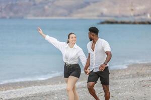 Couple enjoying a joyful moment while walking hand in hand on the shoreline at Playa del Zapillo in Almeria, Spain photo