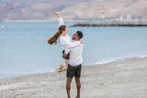 A joyful couple embraces on the beach at Playa del Zapillo, Almeria, enjoying a sunny day and creating lasting memories photo