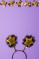 New Year's decor in the form of a golden star shape with black colour text Happy New Year , and christmas decoron purple background.Copy space.Top view photo.Flatlay.Vertical photo. photo
