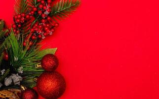 Top view photo christmas spruce branch,christmas tree toys on red background for greeting card. Xmas backdrop with space for text.Copyspace.