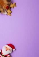 Top view photo christmas plush deer toy and funny Santa Claus plush toy on purple background for greeting card. Xmas backdrop with space for text.Copyspace.Vertical photo.