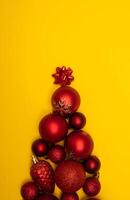 Top view photo tree lined with Christmas tree decorations of red colour on yellow background for greeting card. Xmas backdrop with space for text.Copyspace.Vertical photo.Close up.