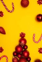 Top view photo tree lined with Christmas tree decorations, christmas tree toys of red colour, christmas lollipops on yellow background for greeting card. Xmas backdrop with space for text.Copyspace.Vertical photo.