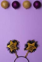 New Year's decor in the form of a golden star shape with black colour text Happy New Year , christmas tree toys on purple background.Copy space.Top view photo.Flatlay.Vertical photo. photo