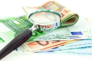 euro notes with magnifier on white background photo