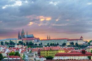 Stunning view of the Prague Castle and other historical buildings in the Czech capital city of Prague. The sky is a mix of blue and light grey clouds with a hint of sunlight peeking through. photo