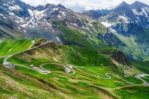 The road winds its way up the mountainside, offering stunning views of the Alps. The lush green landscape is dotted with wildflowers, and the air is fresh and invigorating. photo