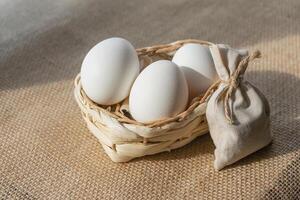 White eggs in a basket on a background of burlap photo