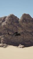A helicopter flying over a desert with a rock formation in the background video