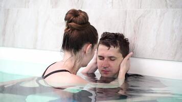 Couple sharing intimate moment in indoor pool gentle touches and tender smiles capture serenity and connection. video