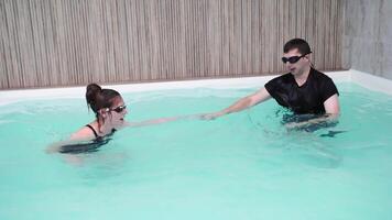 Swimming lesson progression in indoor pool trainer guiding swimmer through relaxation and confidence building techniques. video