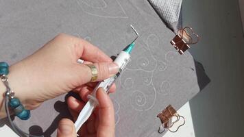 Crafting art closeup of intricate designing with precision pen and metal paper clips on soft gray fabric surface. video