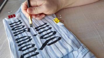 Artistic handpainted fabric design creation with bold black lettering in progress over multiple frames capturing the craftsmanship and precision. video