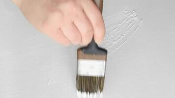Artist smooths white paint on canvas with brush strokes for textured background creation. video