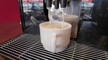 Espresso machine pouring fresh coffee into a cup with frothy crema in cozy cafe setting. video