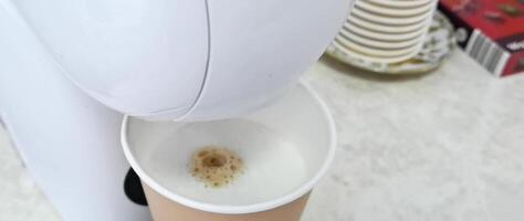 Automated coffee machine dispensing fresh brew foam into cup in modern kitchen setting. video