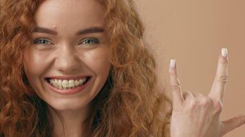 A woman with vibrant curly red hair gazes directly at the camera, showcasing her striking green eyes. The neutral background emphasizes her features, creating an engaging visual focus. video