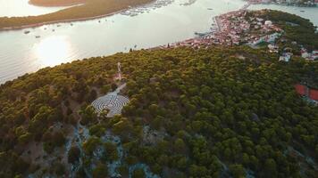 Aerial view of hill covered with forest trees and circular labyrinth on top video