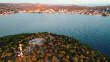 Aerial view of hill covered with forest trees and circular labyrinth on top video