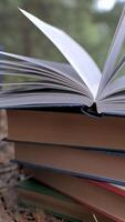 Stacked books in the forest. The concept of learning, reading, and knowledge. Close-up. Blurred background. Vertical video