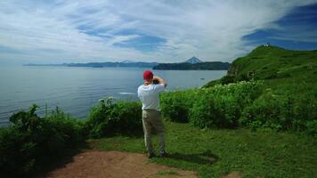 Man In Red Hat Admiring Nature And Taking Pictures By Camera, Rear View, Trip To Mountains In Summer video