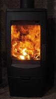 Embers dance in the warmth of a vertical fireplace, creating a cozy atmosphere perfect for winter evenings. The flickering flames illuminate the surrounding dark space. Vertical footage video