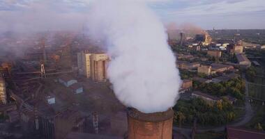 Industrial zone with a large pipe thick white smoke is poured from the factory pipe. Pollution of the environment. a pipe with smoke. Old factory near the river in Kamenskoye, Ukraine. Aerial view. video