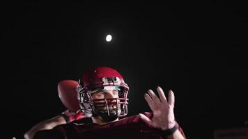 An American football player practicing throwing and catching the ball on a field video