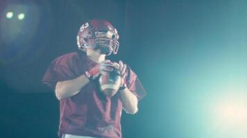 An American football player practicing throwing and catching the ball on a field video