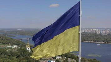 Aerial view of The largest flag of Ukraine is flying against the backdrop of the city of Kyiv and the Dnieper River. 4K video