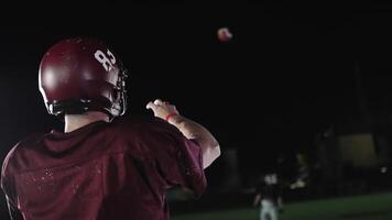 An American football player practicing throwing and catching the ball on a field video