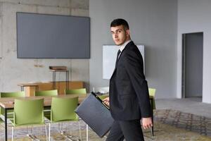 A determined businessman in a black suit confidently walks through the office, embodying professionalism and focus as he heads towards new challenges photo